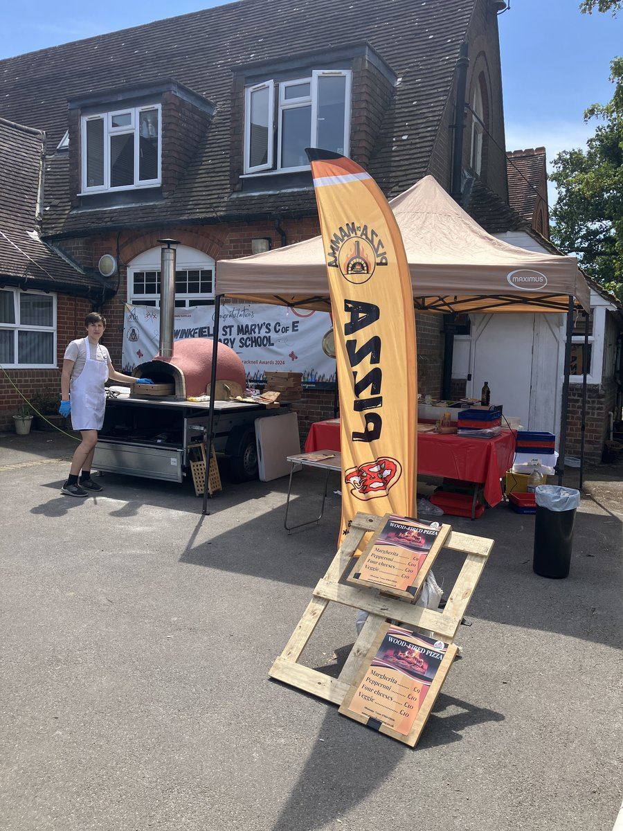 Pink dome wood-fired pizza oven and banner at a school summer fair