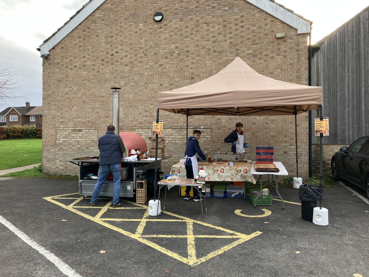 Trailer-mounted wood-fired pizza oven under canopy at outdoor event