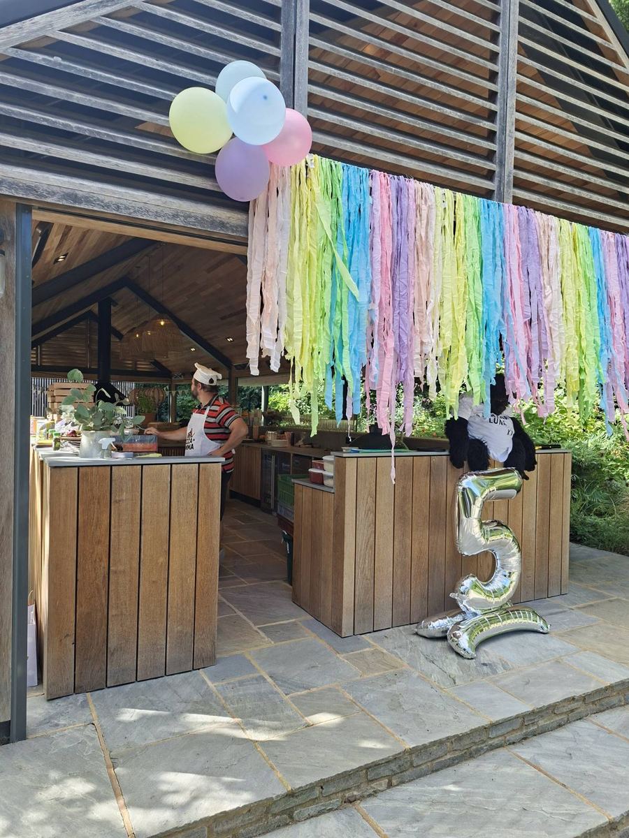 Birthday party setup with balloons and chef at the pizza counter