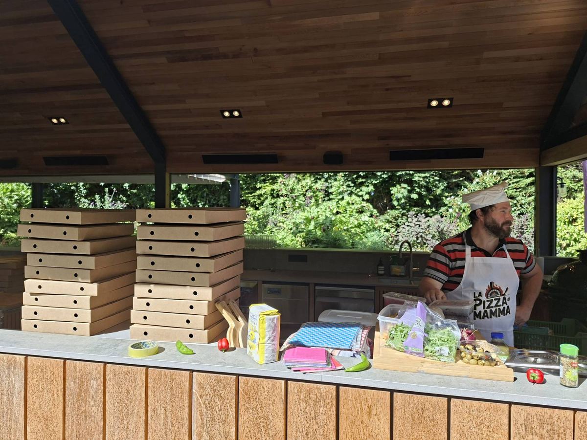 Chef prepping fresh toppings at an outdoor pizza counter