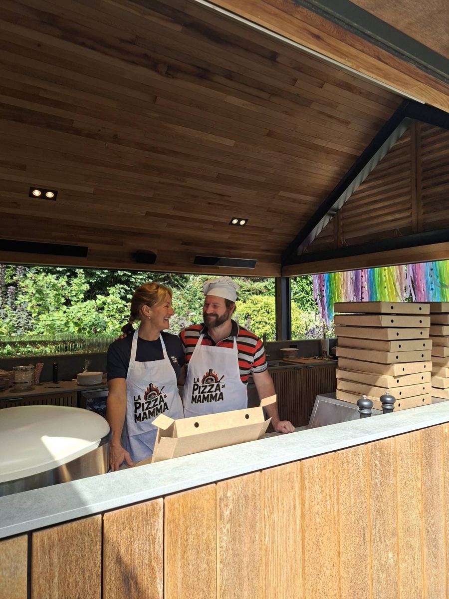 Two Pizza di Mamma team members in aprons prepping at the stall