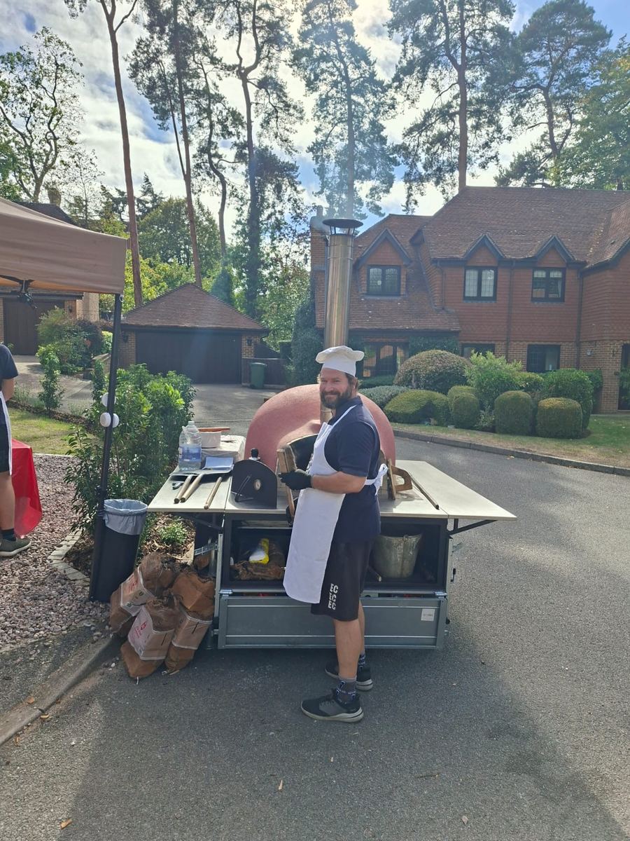 Chef in toque working a trailer-mounted wood-fired oven