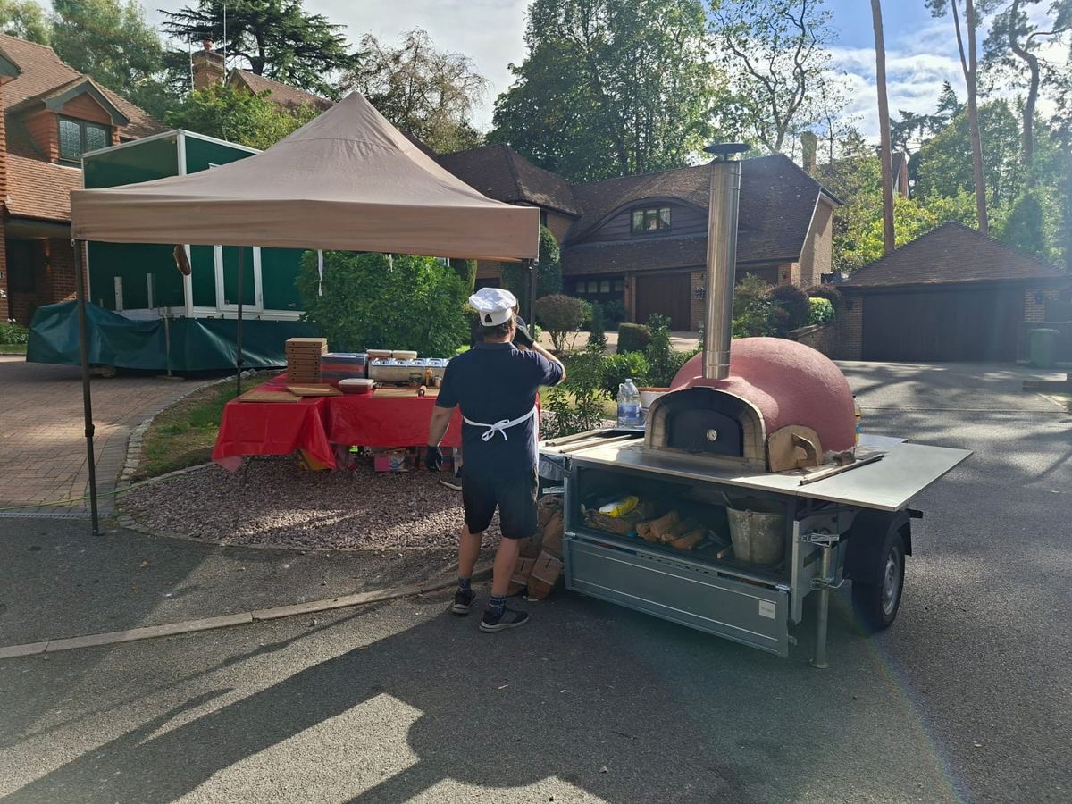 Chef preparing at a mobile pizza oven trailer event setup