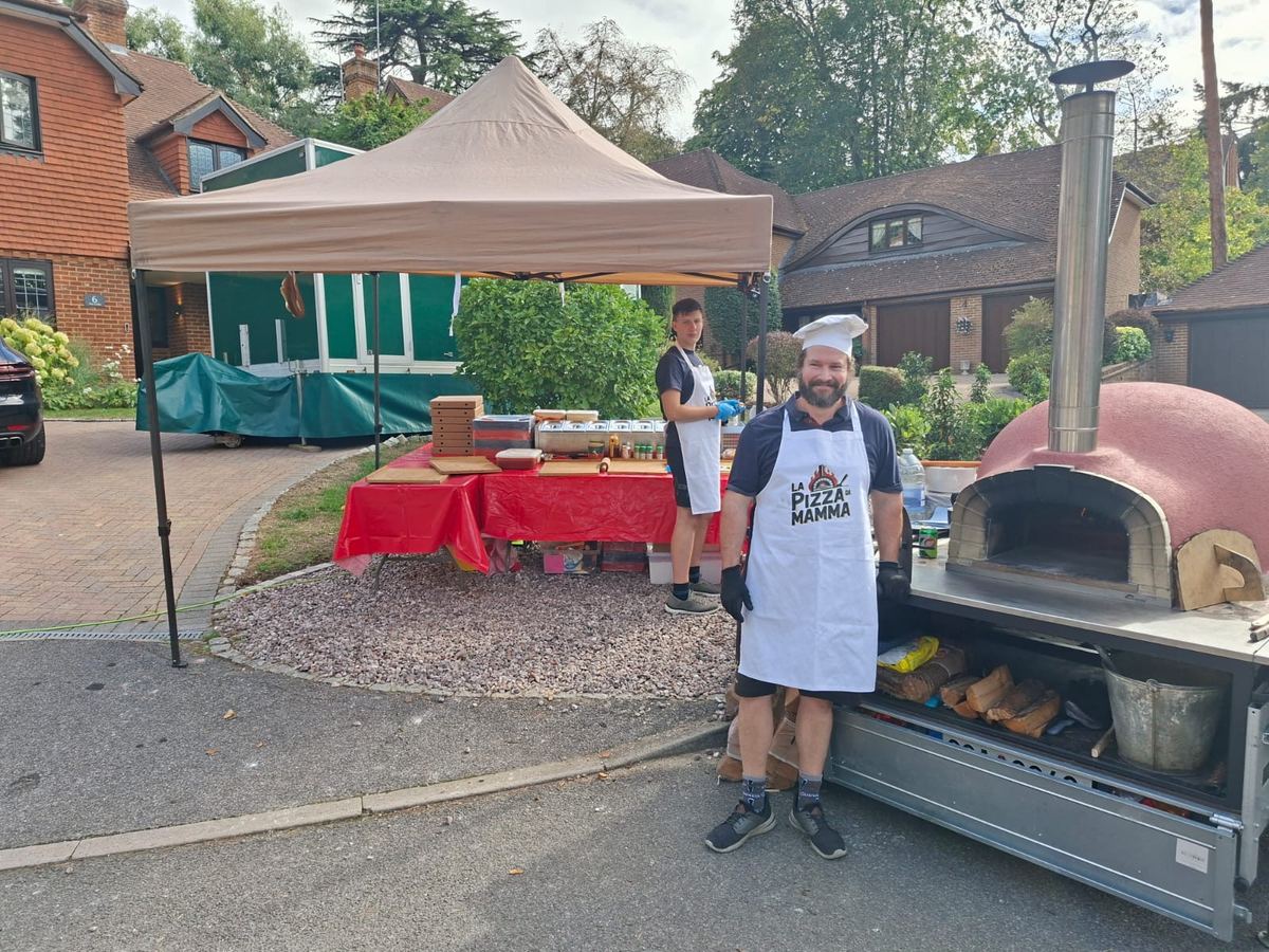 Wood-fired pizza catering setup with oven trailer and prep table